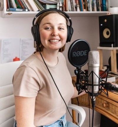 A woman smiling in a recording booth.